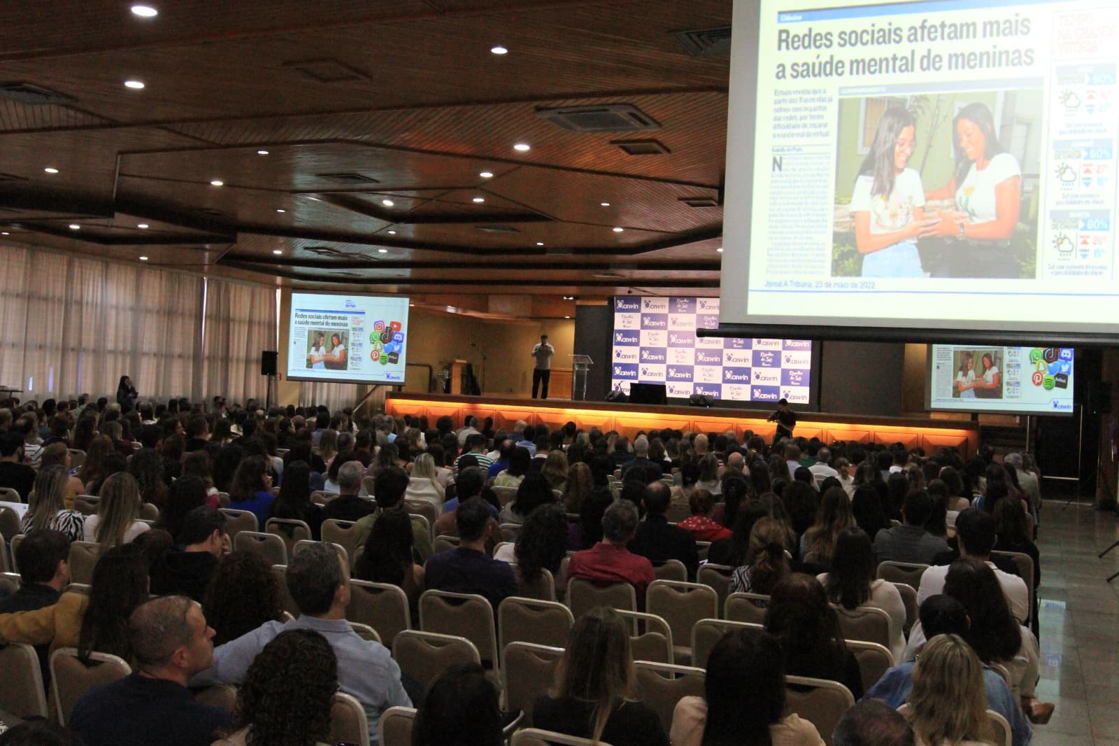 Auditório grande e lotado durante palestra, com telas exibindo conteúdo sobre redes sociais