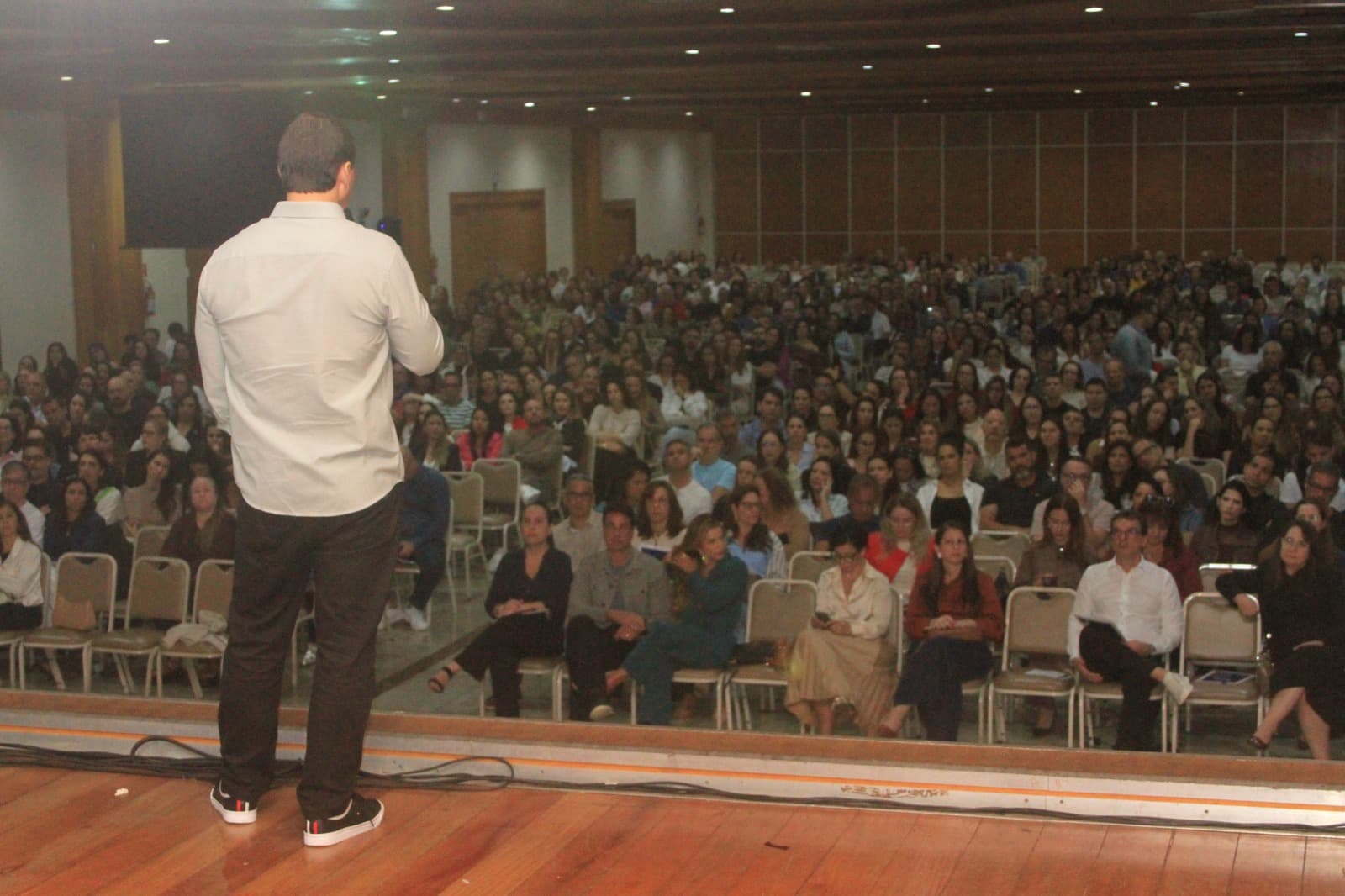 Eduardo Pinheiro no palco, de pé diante de um auditório lotado durante uma palestra sobre segurança digital